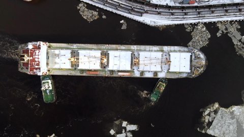 Aerial top timelapse view of cargo ship and pilots who help to moor at port in winter. 