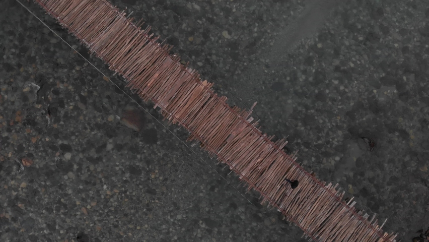 Old wooden suspension bridge over a mountain river, top view of an abandoned bridge, d-cinelike, no color grading