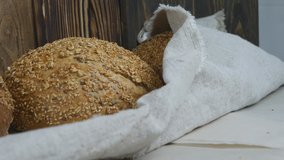 baker's hands in gloves put fresh loaves of bread on burlap cloth. Bread only from the oven, warm, sprinkled with sunflower, oat and flax seeds. Dolly Bread Shooting - Powered by Shutterstock - Get 15% off with code: PIKWIZARD15