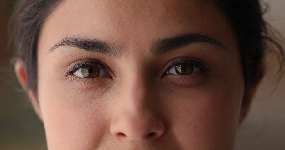 Extreme close up of upper part of indian female face with kind brown eyes. Happy mixed race woman looking at camera, showing positive sincere emotions, body language, eyesight care, skincare concept. Royalty-Free Stock Footage #1066471492