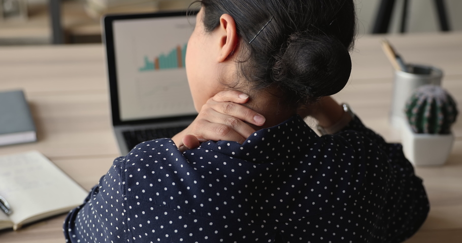 Back rear head shot shoulder view exhausted young indian woman massaging neck, suffering from pain or inflammation processes due to long sedentary computer work at home office, feeling unhealthy. | Shutterstock HD Video #1066471579