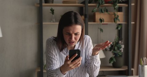 Stressed nervous young woman looking at cellphone screen, feeling frustrated of receiving message or email with bad news. Unhappy millennial female user dissatisfied with bad electronic device work.