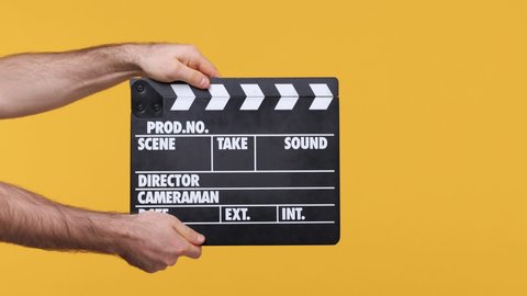 Cropped close up man male hold in hand classic director clear black film making clapperboard isolated on yellow background studio. Copy space commercial promo mock up Cinematography production concept