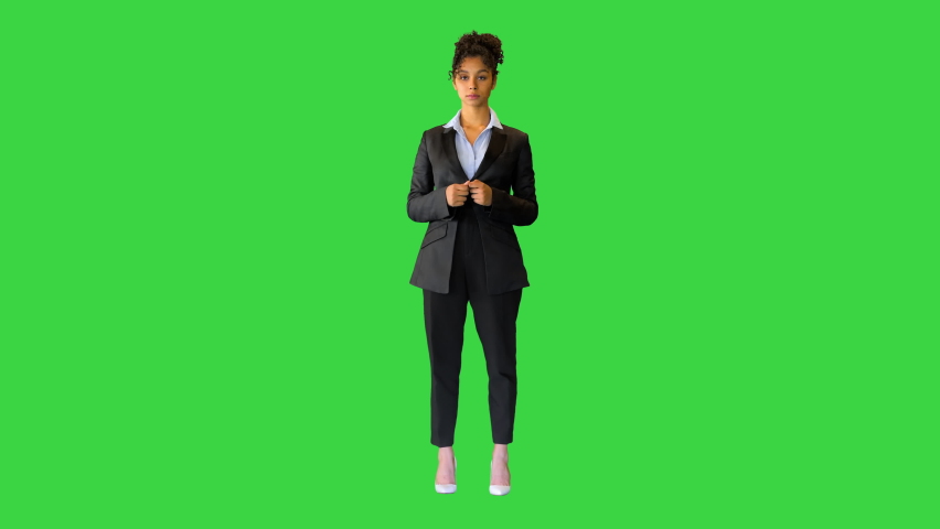 Young black lady talking on camera and pointing at something on a Green Screen, Chroma Key. Royalty-Free Stock Footage #1066477810