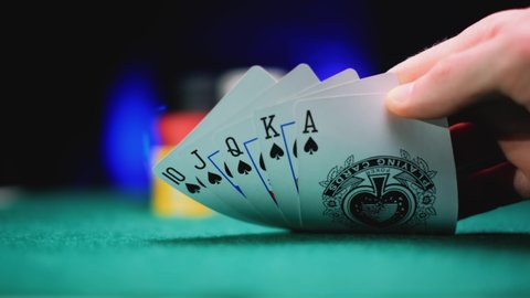 Poker table during a game. A player is holding cards in hand. Chips and cards on the table.Theme of gambling.