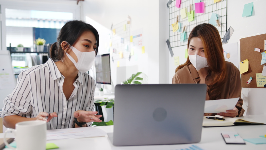 Asia businesspeople using computer presentation meeting brainstorming ideas about new project colleagues and wear protective face mask back in new normal office. Lifestyle and work after coronavirus. | Shutterstock HD Video #1066478557