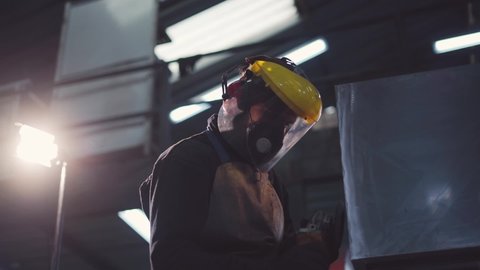 The man polished the metal. Interior of an industrial workplace with a man polishing a piece of metal creating fire sparks. Leveling material.