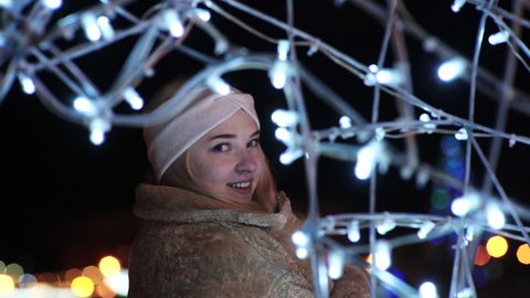 Girl posing against the backdrop of urban Christmas illumination.