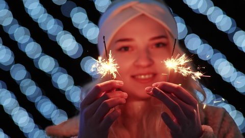 Girl with sparklers on the background of the Christmas lights of the evening city.