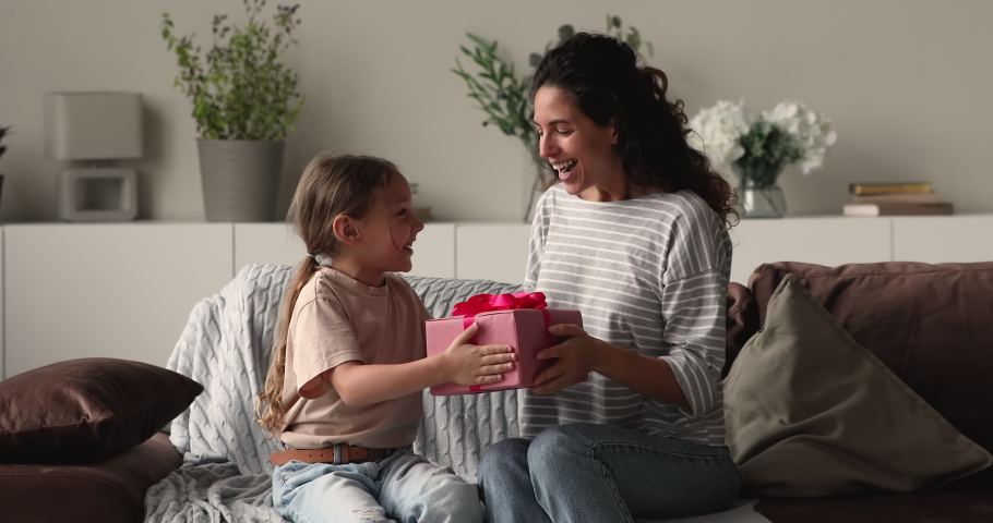 Little daughter congratulates mom gives her gift box. Mommy cover eyes with hands in anticipation receive surprise from small kid. Family celebrate life event, Mother Day expressing love care concept Royalty-Free Stock Footage #1066486708