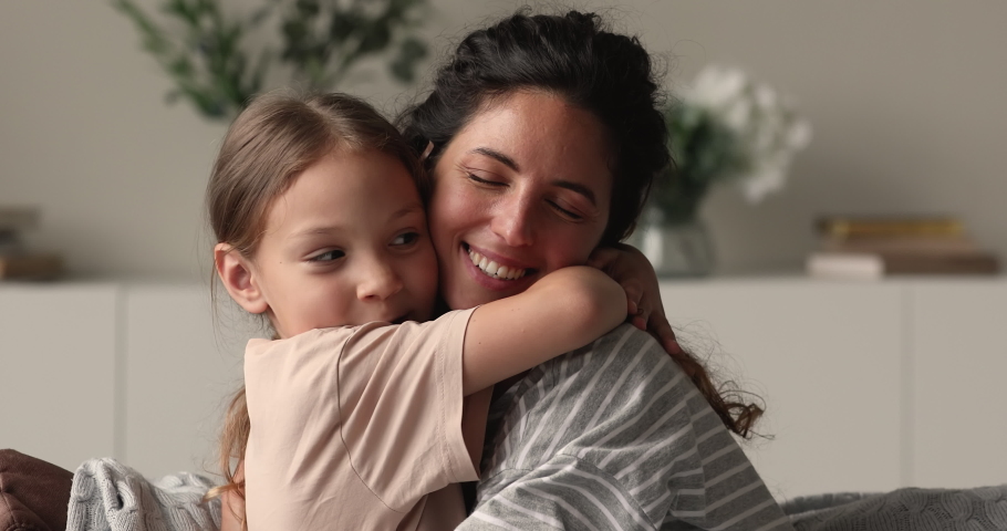 Close up portrait loving mother cuddles little daughter, family sit on sofa touch noses feel unconditional love show devotion, express caress. Caring mom, adopted kid, Mothers Day celebration concept Royalty-Free Stock Footage #1066486714