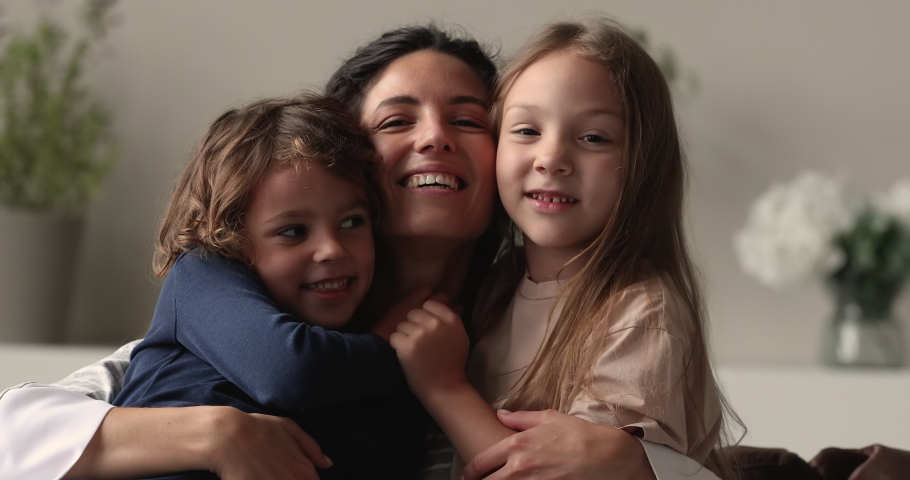 Close up portrait loving mom hug little children. Caring mum embrace preschool son daughter sit together on couch smile look at camera. Family celebrate Mother Day, happy motherhood, adoption concept Royalty-Free Stock Footage #1066486843