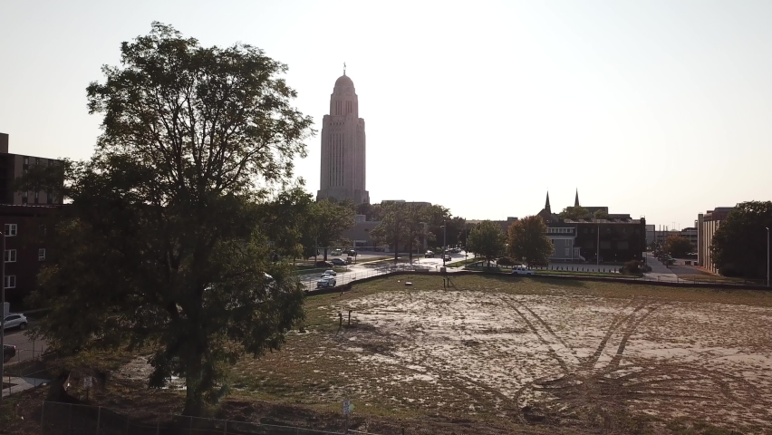 Aerial Lincoln Nebraska State Capitol Building Rise Over Trees Looking Into Evening Sun