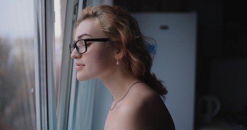 Woman looks through window wearing optical eyeglasses, myopia 