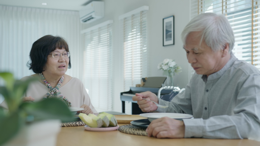 Attractive young senior asian citizen couple happy sit, talk, eat soup for healthy nutrition breakfast meal on dining table at home in morning in routine lifestyle in old asia nursing in-home care. Royalty-Free Stock Footage #1066489687