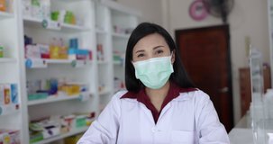 Asian women pharmacist wearing masks standing in pharmacy to measure the fever detector by infrared thermometer of visitors coronavirus or COVID-19 protective concept 4K video focus on the eye 