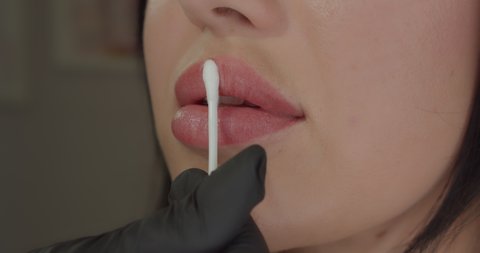Extreme close up of sexy woman lips with botox. Moisturizing the lips
