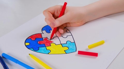 World Autism Awareness day. Children's hand draws heart from multi-colored puzzles. Mental health care concept