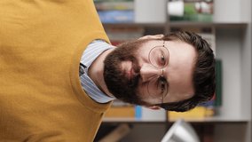Man thumb up. Vertical video of positive smiling bearded man in glasses in office or apartment room looking at camera and shows his thumb up. Close-up and slow motion
