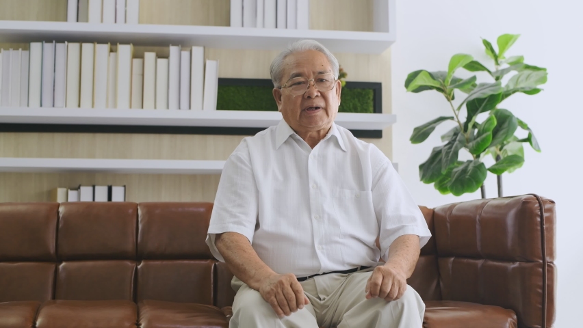 Family concept of 4k Resolution. An elderly Asian man is giving an interview about his health in the living room. Royalty-Free Stock Footage #1066519246