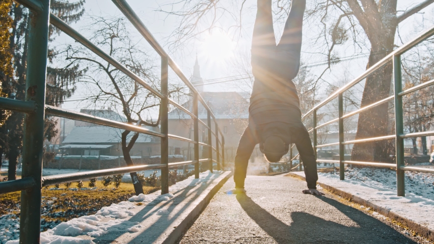 Man performs handstand outdoor in winter 