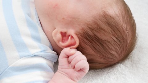 Closeup of mother using cotton swabs to clean little baby's ears from ear wax. Concept of babies and newborn hygiene and healthcare. Caring parents with little children