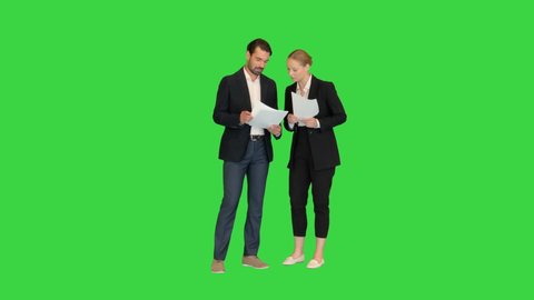 Two young business people talking about documents on a Green Screen, Chroma Key.