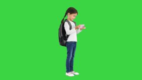 School girl with backpack watching something funny on her pink phone and laughing on a Green Screen, Chroma Key.