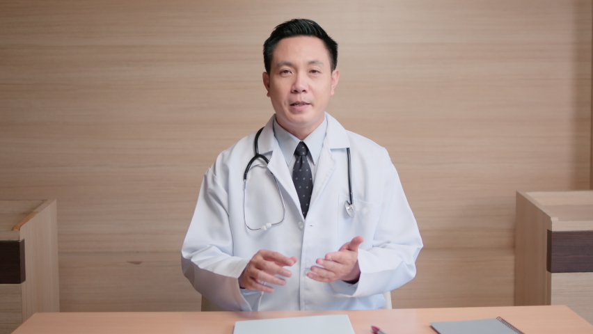 Asian male doctor look at camera, online video call remote talking to patient, prescribe medicine. Tele medical, telehealth, hospital clinic health care service, or internet technology concept | Shutterstock HD Video #1066522873