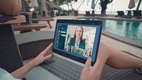 Nice-looking woman chilling at outdoor terrace by pool having video conference with colleagues brainstorming and sharing ideas