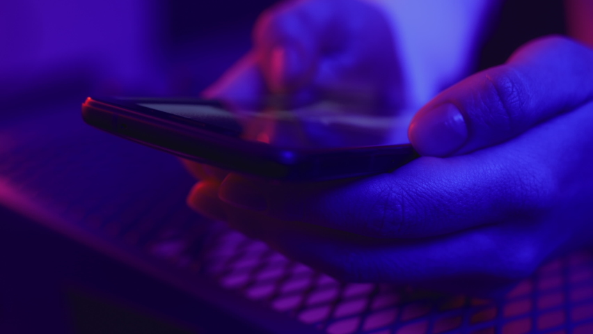 Use of mobile phone in shining neon light of event indoors. Creative vivid color of ultraviolet red and blue. Hands of person swiping photos left. Social media photograph closeup in stylish dark room Royalty-Free Stock Footage #1066528120