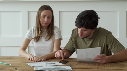 Stressed young couple calculating monthly home expenses, credit card bills payment. 