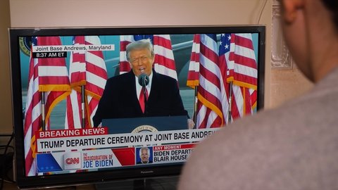 Paris, France - Jan 21, 2021: Donald Trump last speech - Woman watch TV breaking news of Presidential Inauguration ceremony of Joe Biden the 45th President of United States of America