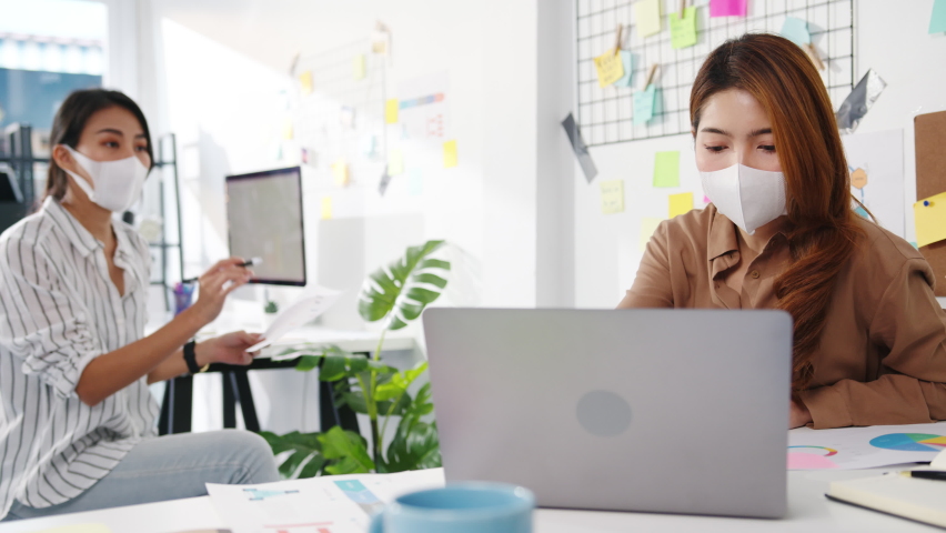 Asia businesspeople using computer presentation meeting brainstorming ideas about new project colleagues and wear protective face mask back in new normal office. Lifestyle and work after coronavirus. | Shutterstock HD Video #1066536655