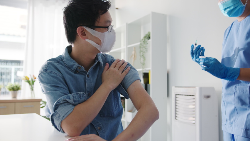 Young Asia lady nurse giving Covid-19 or flu antivirus vaccine shot to senior male patient wear face mask protection from virus disease at health clinic or hospital office. Vaccination concept. Royalty-Free Stock Footage #1066536658