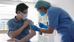 Young Asia lady nurse giving Covid-19 or flu antivirus vaccine shot to senior male patient wear face mask protection from virus disease at health clinic or hospital office. Vaccination concept. - Powered by Shutterstock - Get 15% off with code: PIKWIZARD15