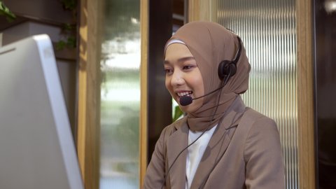 Beautiful asian muslim women wearing hijab working in call center office, Confident islam woman worker in Customer Support smiling joyful to Support Customers