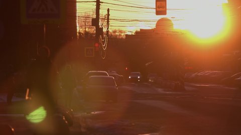 City street at sunset.
The sun sets between the houses. Cars are passing along the city road. Horizontal panning.