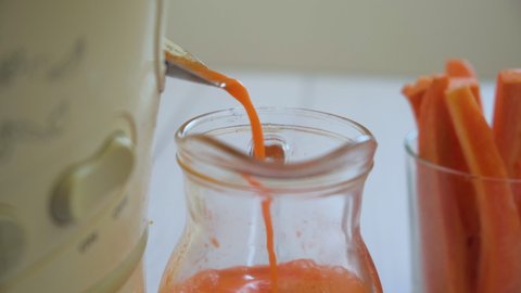Preparation of carrot juice in a juicer. The concept of a healthy diet and a healthy lifestyle. Closeup
