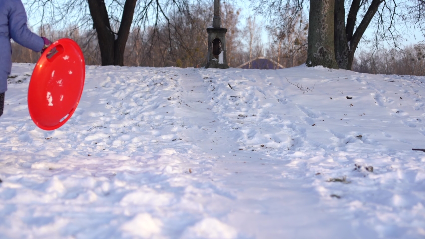 little girl goes downhill on an ice sled down the winter snow-covered hill
