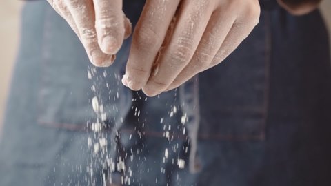 Female hands sprinkles baked goods with flour, slow motion.