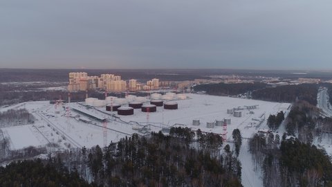 Aerial view of Oil storage near the residential area. A view of the oil storage and multi-storey buildings. Winter evening.
