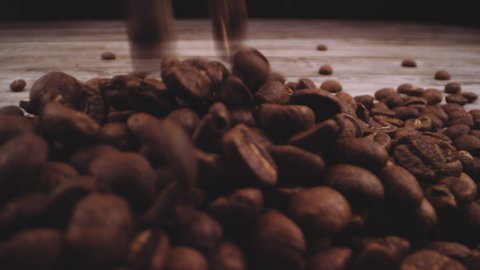 Lockdown Medium Studio Shot Of Roasted Coffee Beans Falling Down Into A Heap On Hard Wooden Surface In Front Of Camera