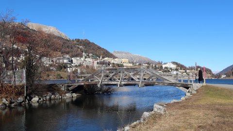 St. Moritz, Switzerland - November 26, 2020: St. Moritz is a high Alpine resort town in the Engadine in Switzerland, at an elevation of about 1,800 meters. Man comes on the bridge at the lake.