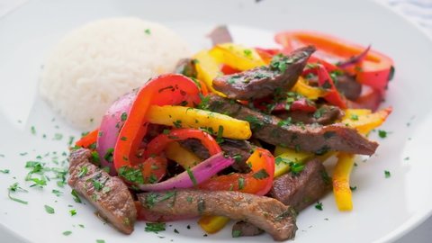 Peruvian cuisine concept. Lomo saltado - fried beef with peppers, onion, potato and rice on white plate.