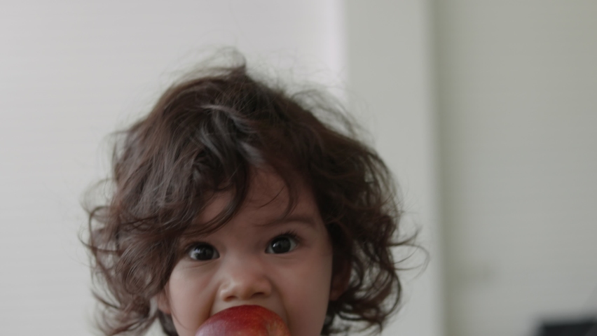 slow motion shot. Cute hispanic baby face Eating a red apple. The baby eats fruit for the first time. A little girl bites a fruit and chews. Concept of tooth and gum development Royalty-Free Stock Footage #1066563886