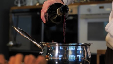 Close-up man pouring red wine into a saucepan