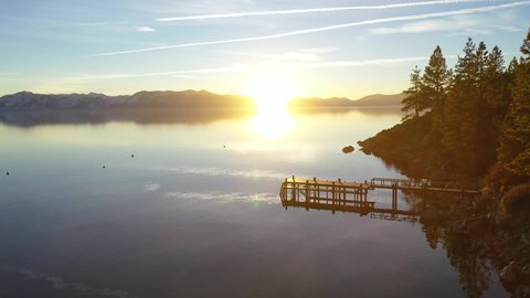 LAKE TAHOE, CALIFORNIA - CIRCA 2020s - Evening sunset drone aerial over Glenbrook, Lake Tahoe, Nevada, past a beautiful pier in the water on the lake.