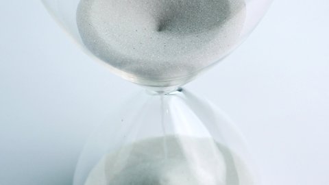 Sand pouring in hourglass, Time concept.