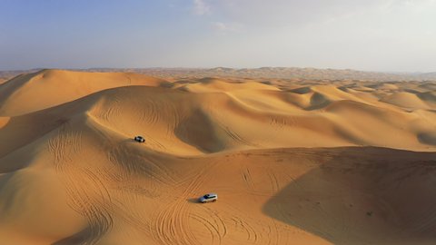 Desert Safari off-roading, group of car or SUV or 4x4 vehicle rides on desert dune barkhan or sand-dune. Aerial drone view